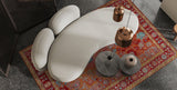Curved cream sofa on an oriental red carpet with copper pendant lights, viewed from above