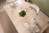 Travertine dining table set with white tableware and avocados, viewed from above